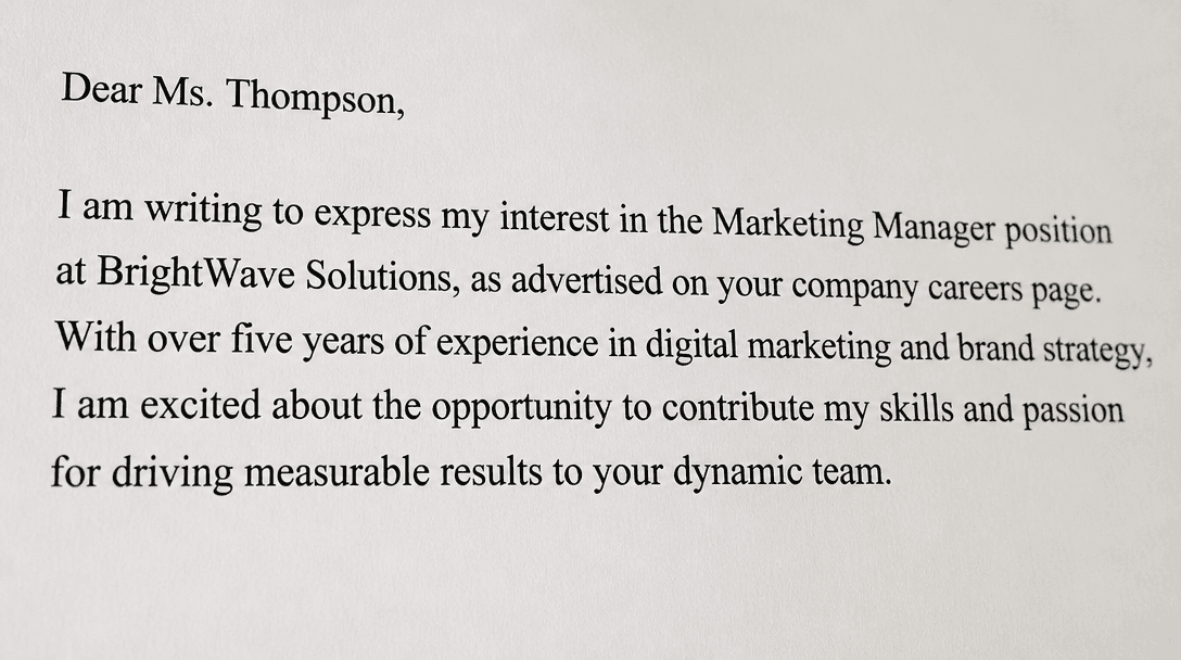 Person writing a cover letter at a clean desk with reference materials